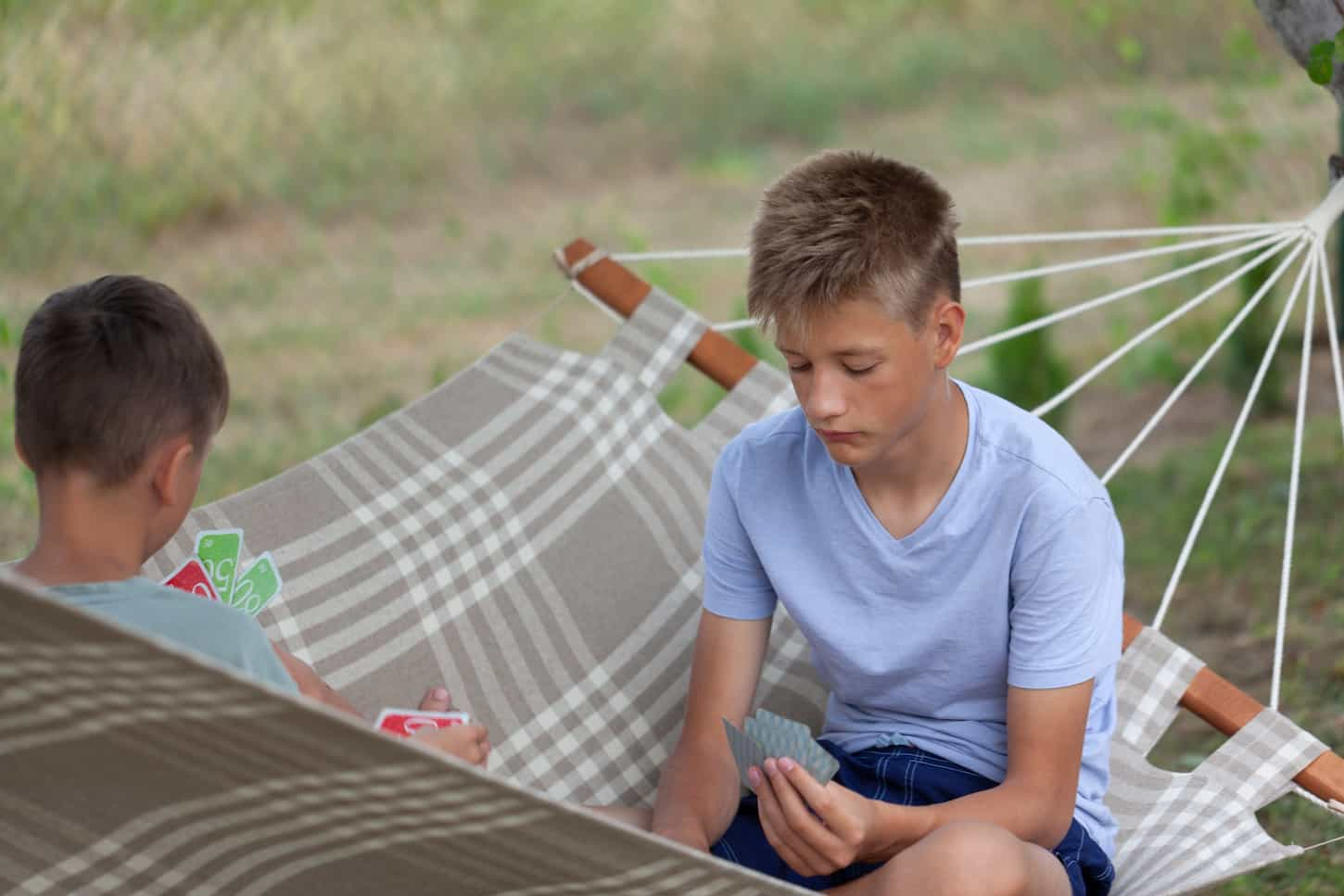 An image of Children playing cards outdoors.