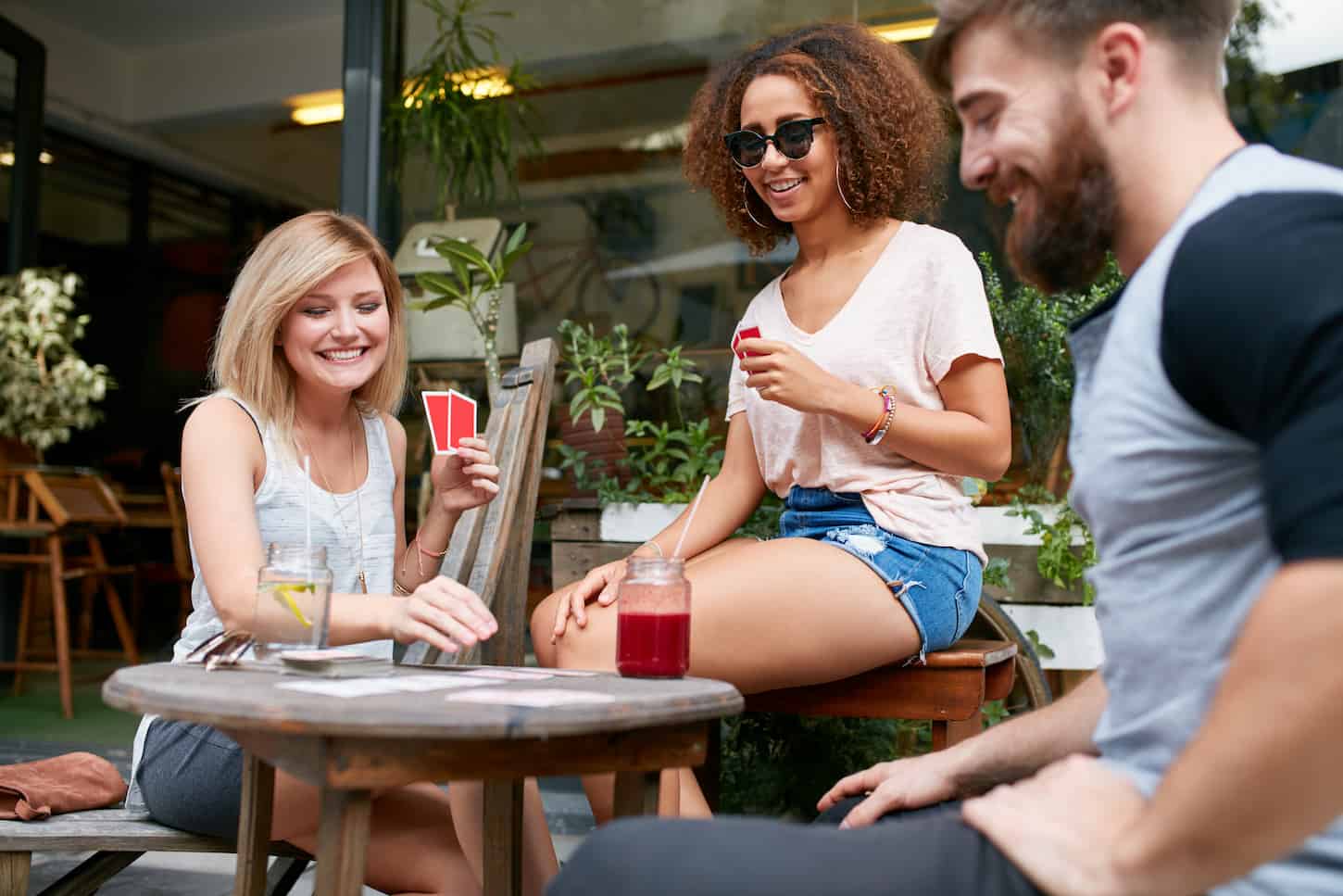 An image of Friends playing a game of cards in a cafe.