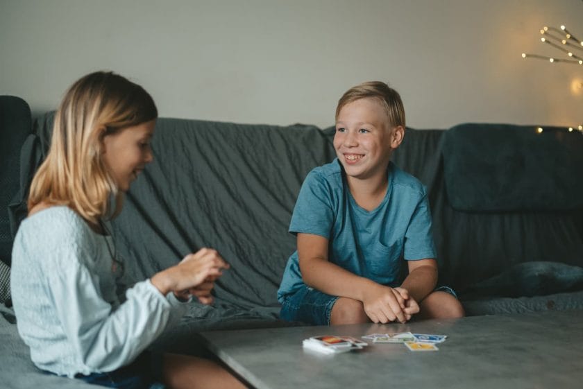 An image of a boy and a girl playing Uno cards in the living room.