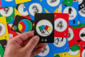 An image of Personal perspective of hand holding black Uno card withdraw four sign.