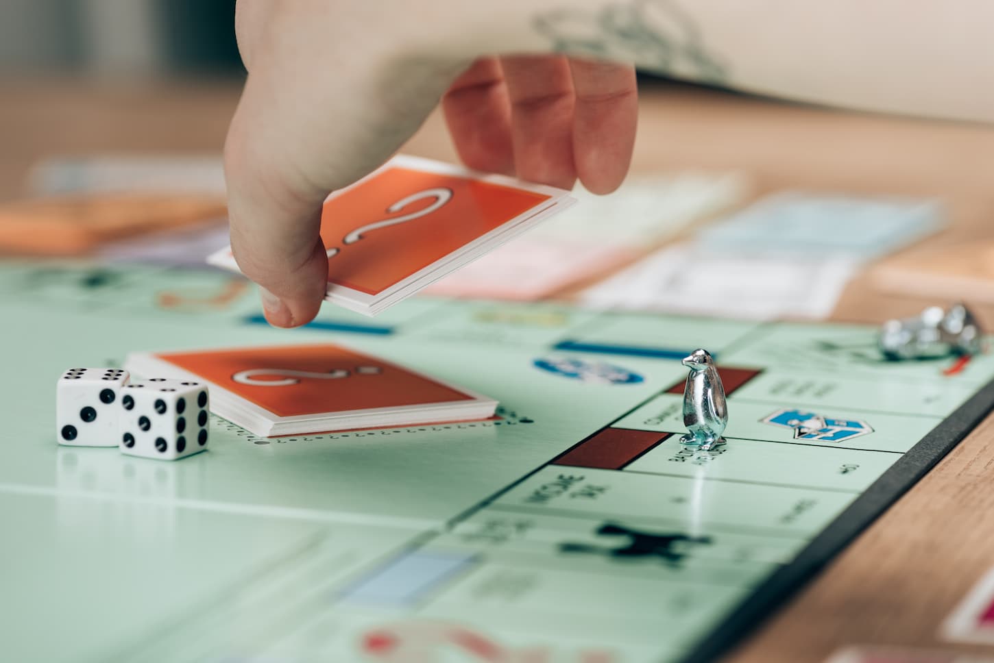 An image of a woman holding a card by dice on monopoly game.