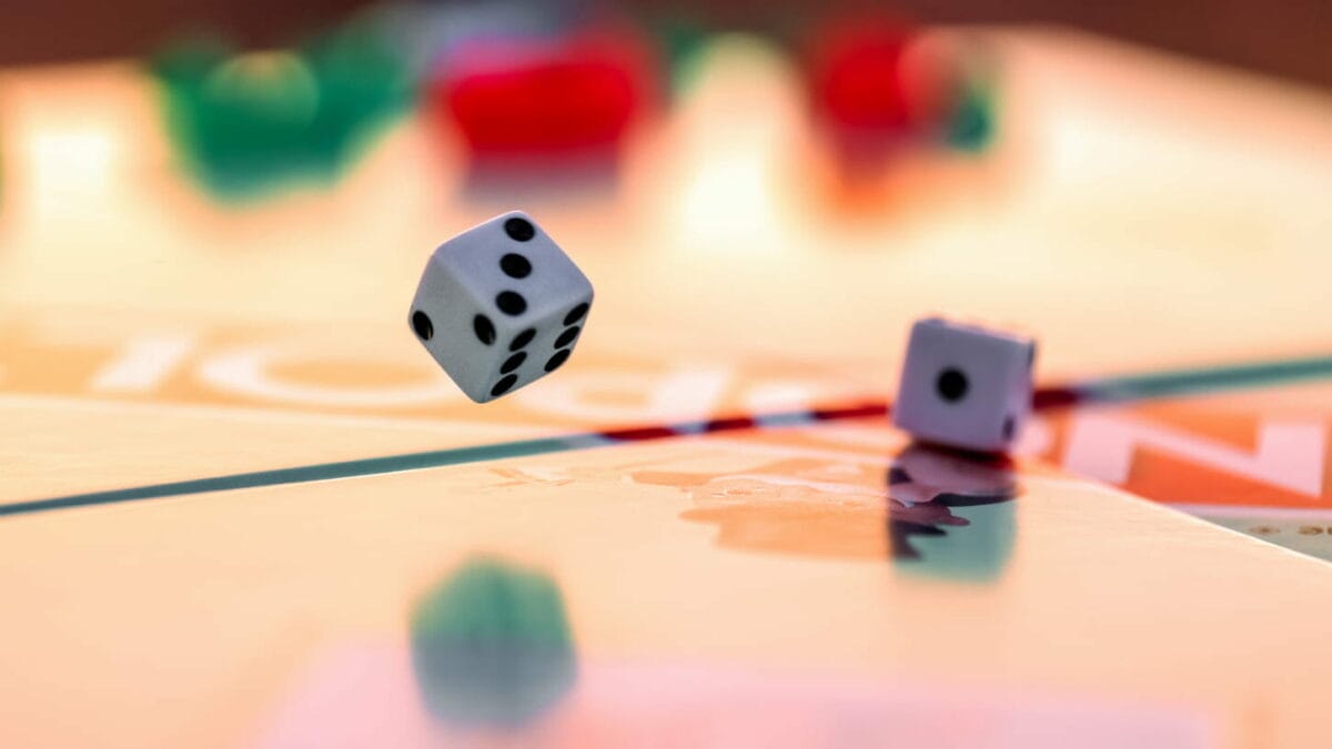 An image of two dice rolling in a background of a monopoly board.