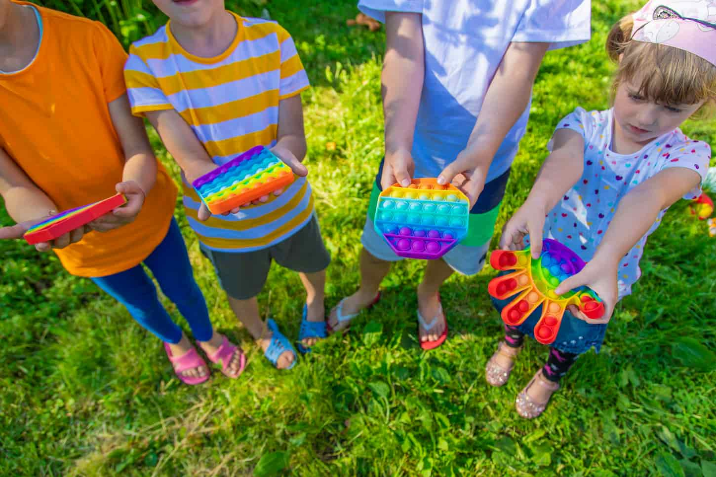 An image of Children playing pop it on the street.