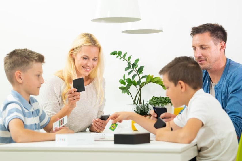 An image of Happy young family playing card game at dining table at bright modern home.