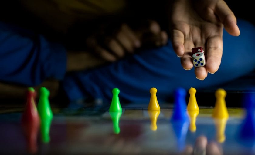 An image of an unrecognizable hand-holding dice playing a board game at home.