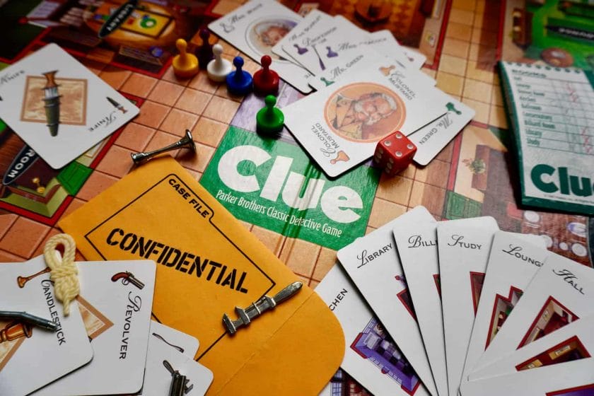 An image of Clue, a murder mystery board game. Known as Cluedo, outside of North America. Parker Brothers 1996 edition. Game pieces, weapons, characters, room cards, dice, board, confidential envelope.