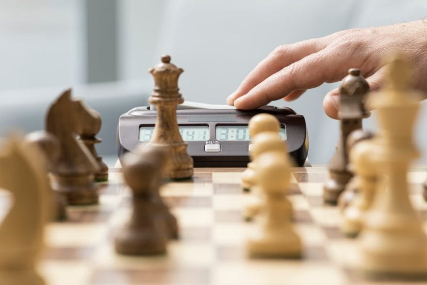 An image of a Chess player hitting the chess clock: chess tournament and competition concept.