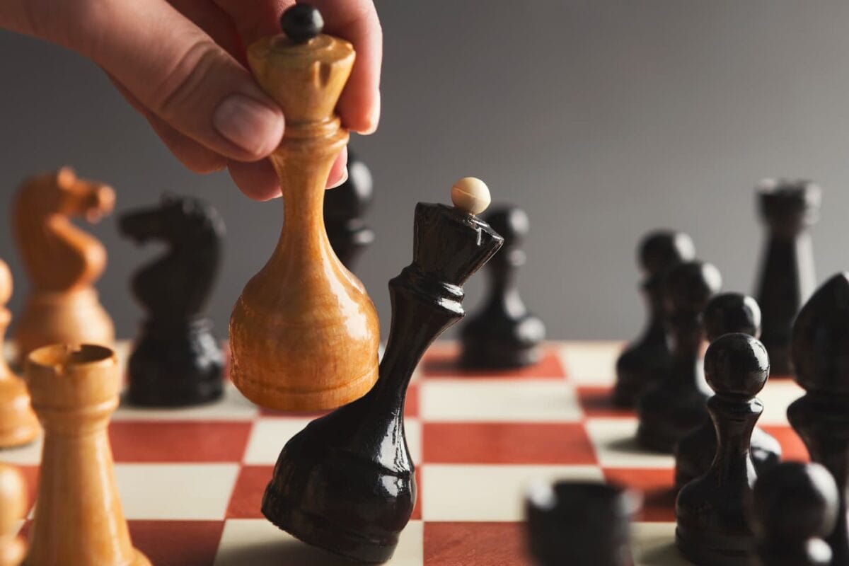 An image of an unidentified Hand taking a checkmate on a chessboard during a chess game.