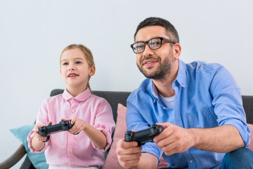 An image of a dad and daughter playing a video game together.
