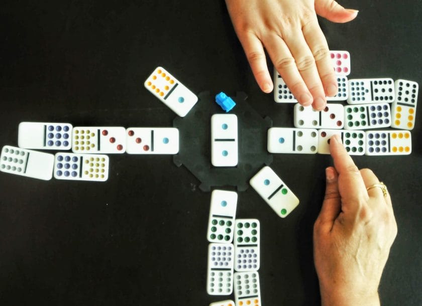 An image of hands playing a game of Dominoes.
