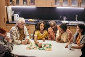 An image of a family playing a board game together in their kitchen.